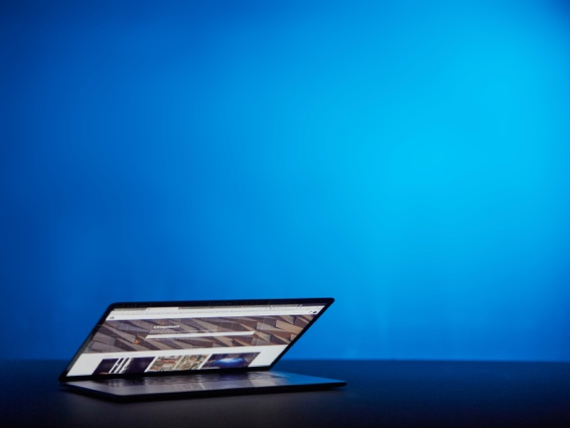 half-open laptop in front an illuminated, blue background