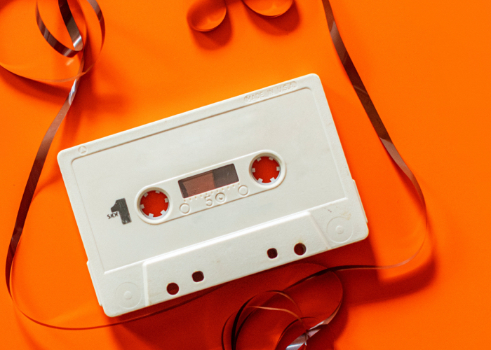 a cassette tape with unwound tape on an orange background